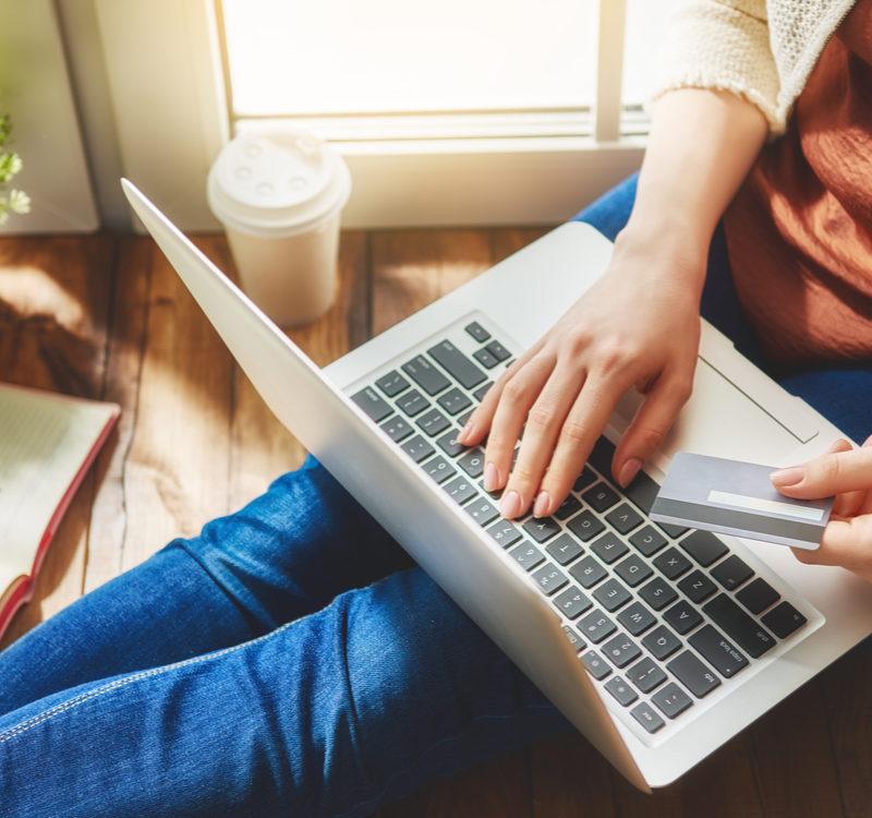 Woman Is Holding Credit Card And Using Laptop Computer. Online Shopping Concept. Close Up.