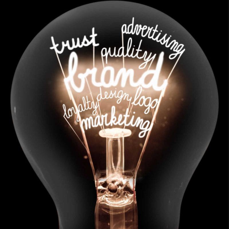 Single Light Bulb With Shining Fibers In A Shape Of Brand, Identity, Value, Marketing And Trust Concept Related Words Isolated On Black Background.
