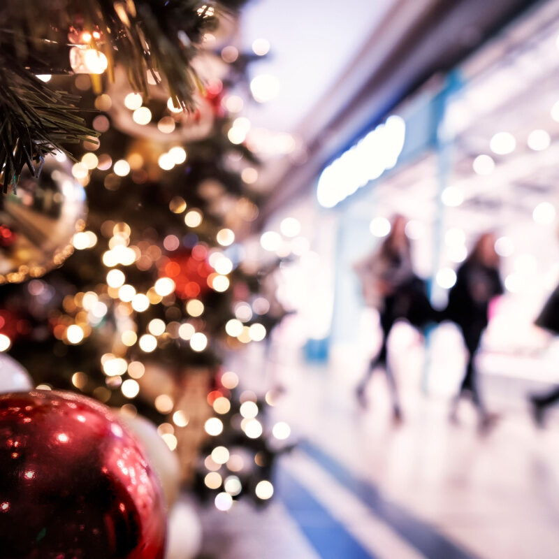 Christmas Rush, Christmas Lights With Silhouettes Of Defocused Shoppers In A Shopping Mall